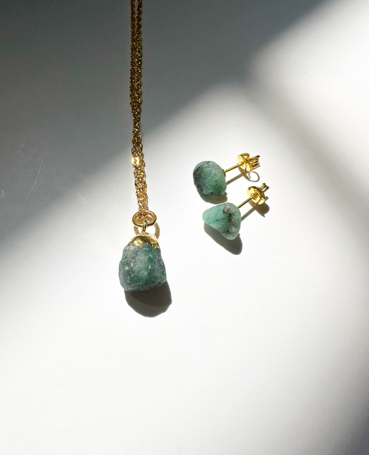 Photo of raw emerald birthstone necklace and matching raw emerald birthstone stud earrings.