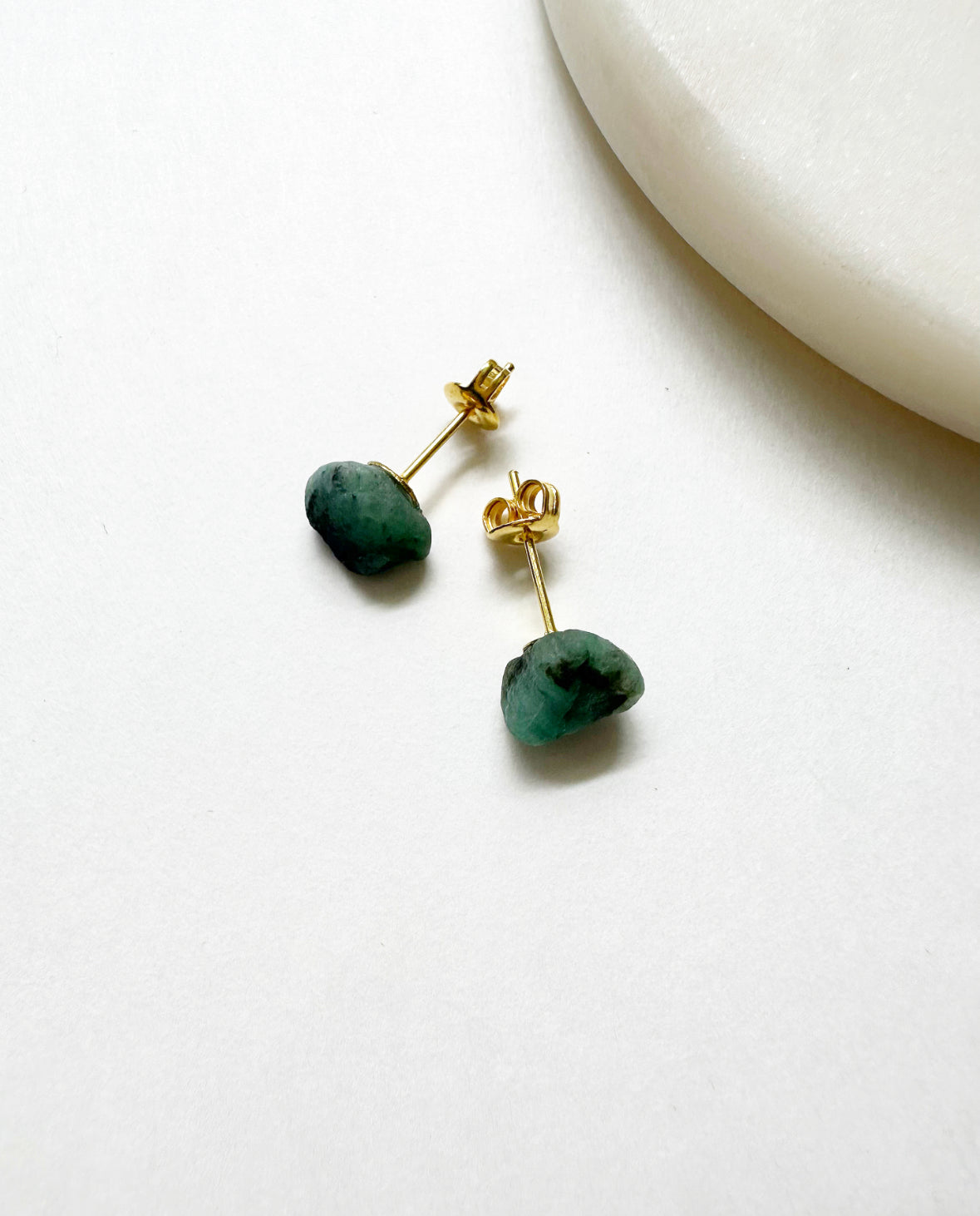 Raw emerald birthstone stud earrings with 14k gold post.