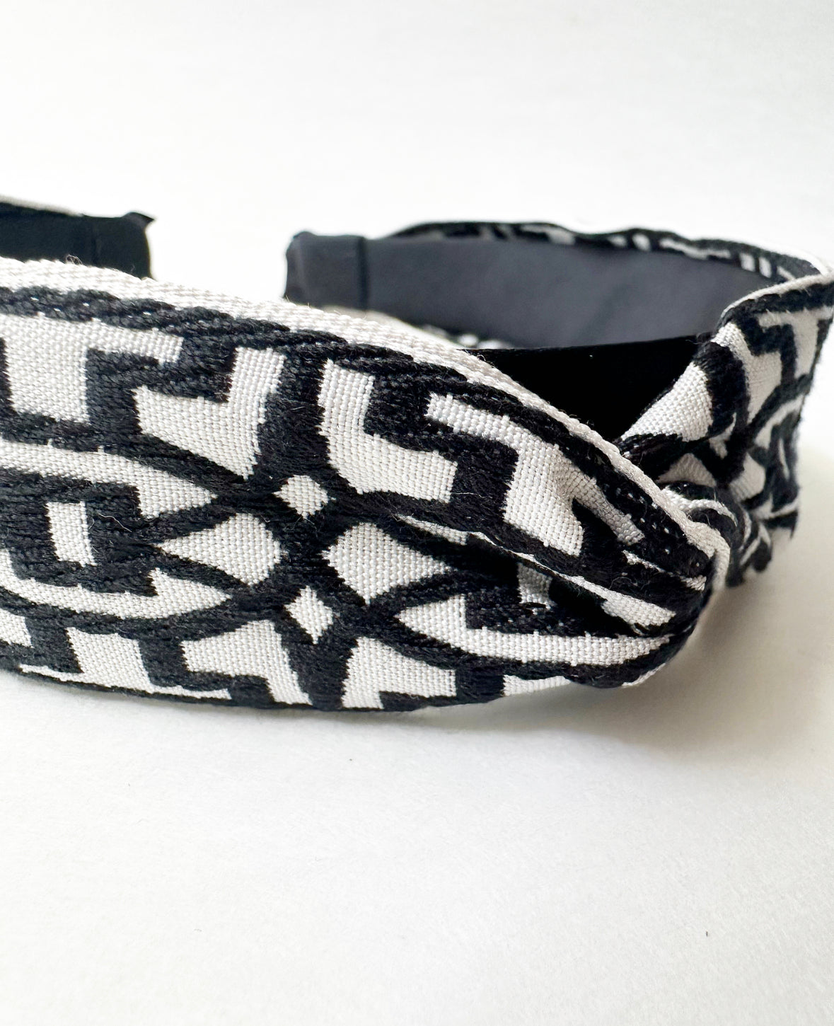 Close-up view of twist detail and embroidery pattern on fabric of the headband in Black/White.
