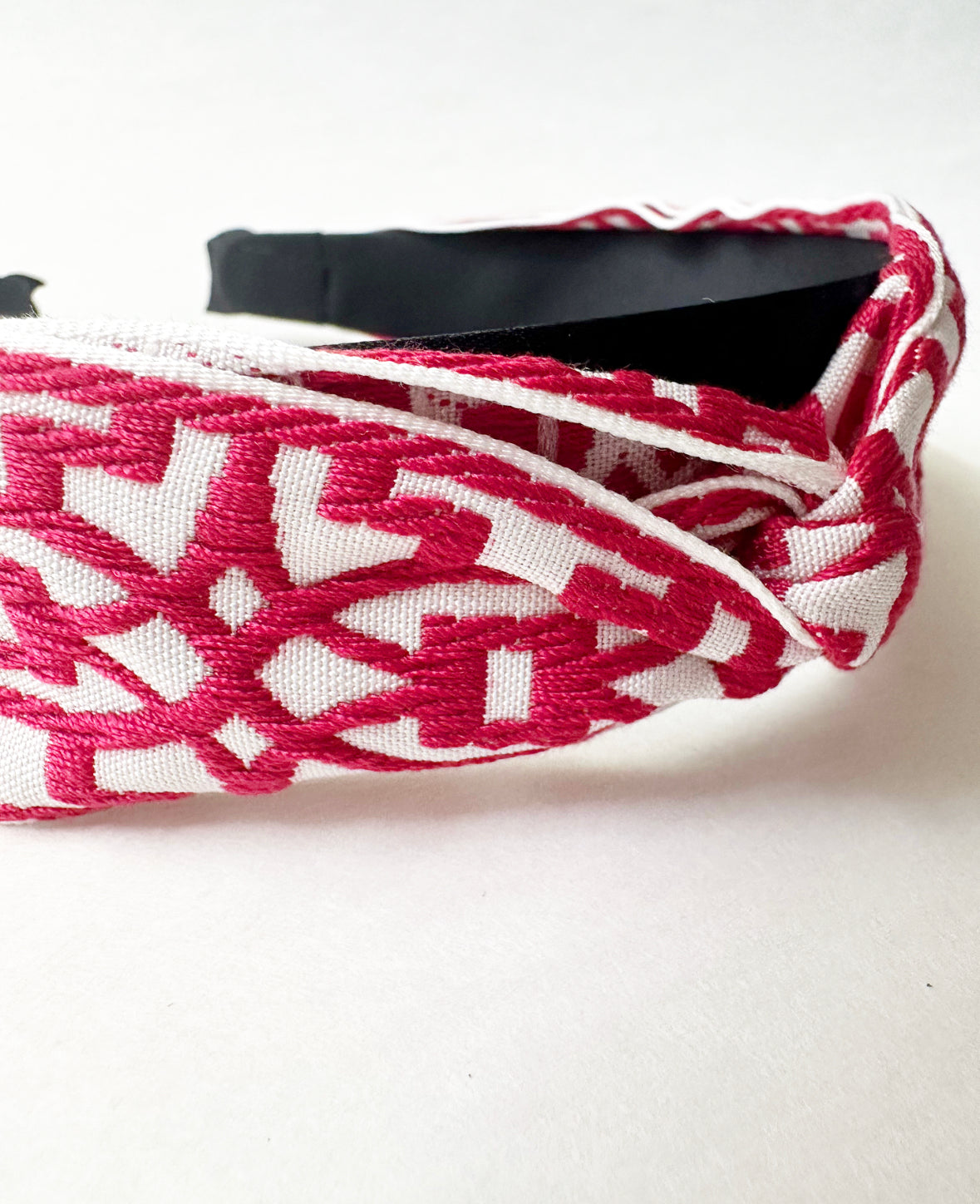 Close-up view of twist detail and embroidery pattern on fabric of the headband in Magenta/White.