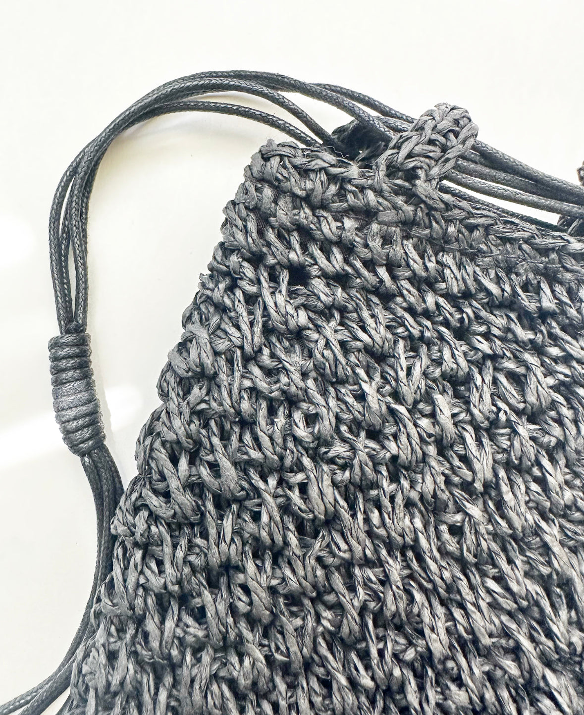 Close-up view of woven detail and strap on black bag.