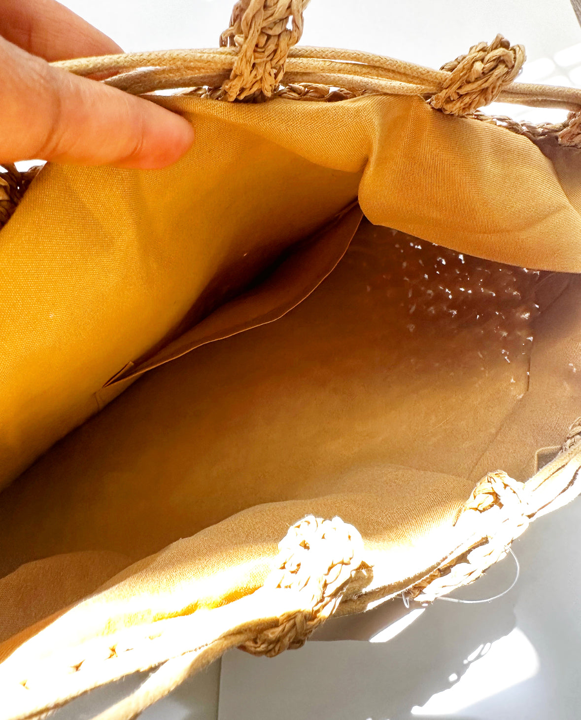 View of lining and pocket on inside of tan bag.