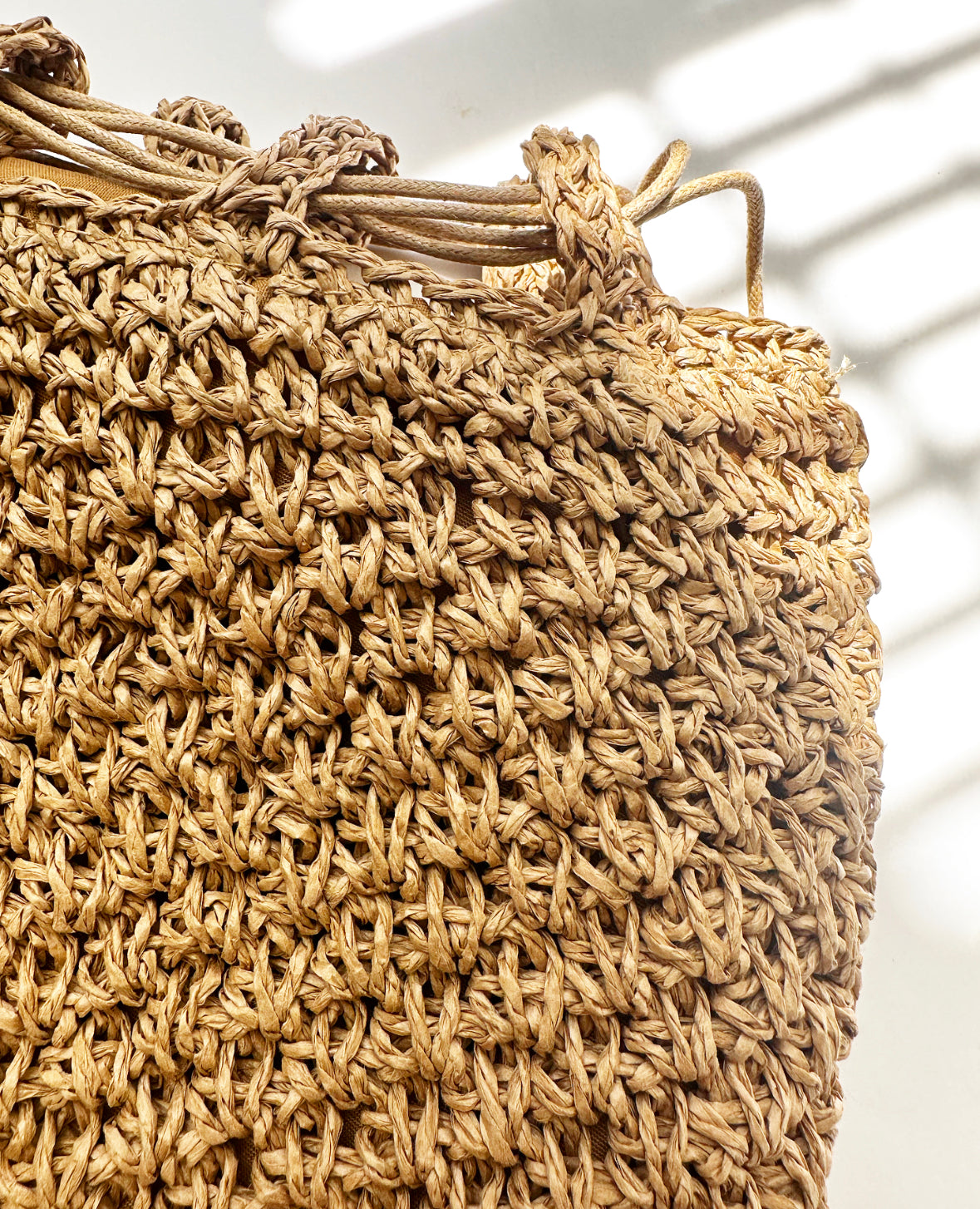 Close-up view of woven detail on tan bag.