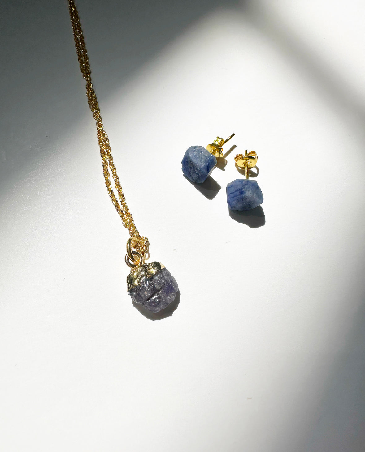 Photo of raw sapphire birthstone necklace and matching raw sapphire birthstone stud earrings.