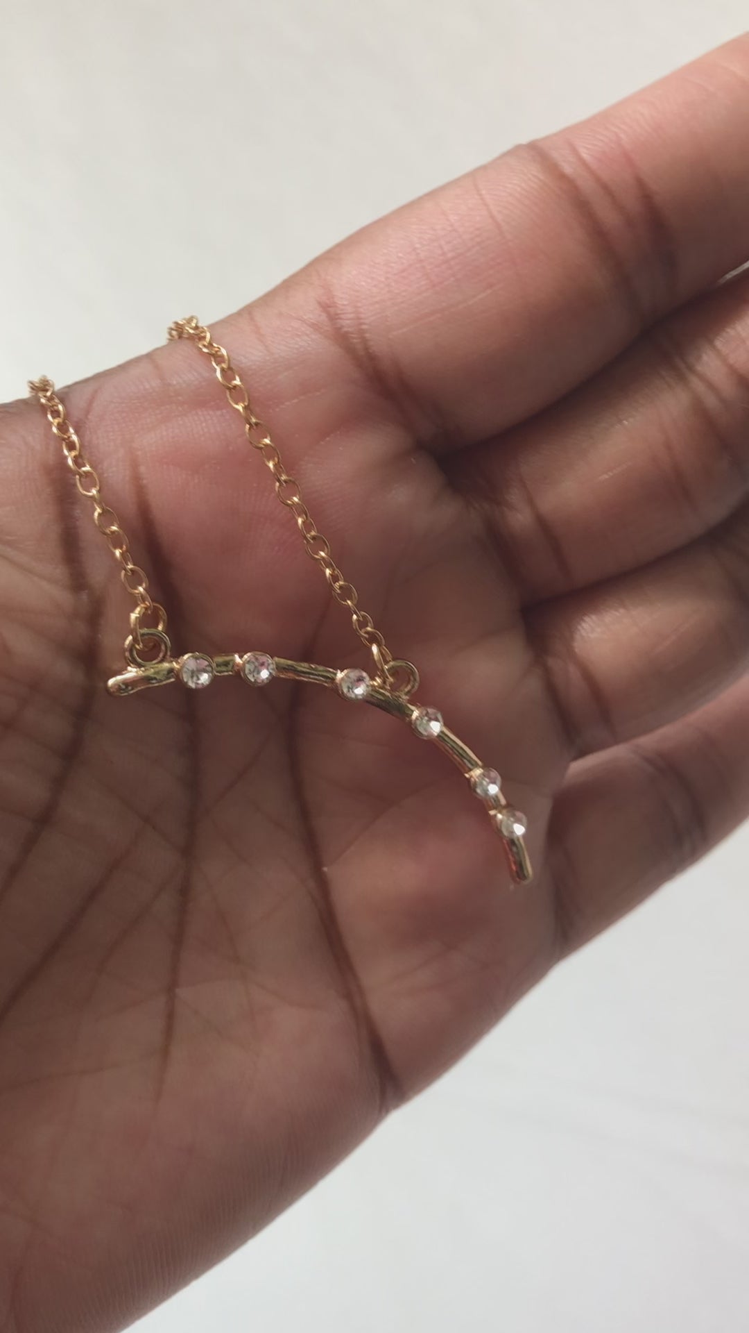 A real-time view of The Other Side Necklace shown on the palm of model's hand.