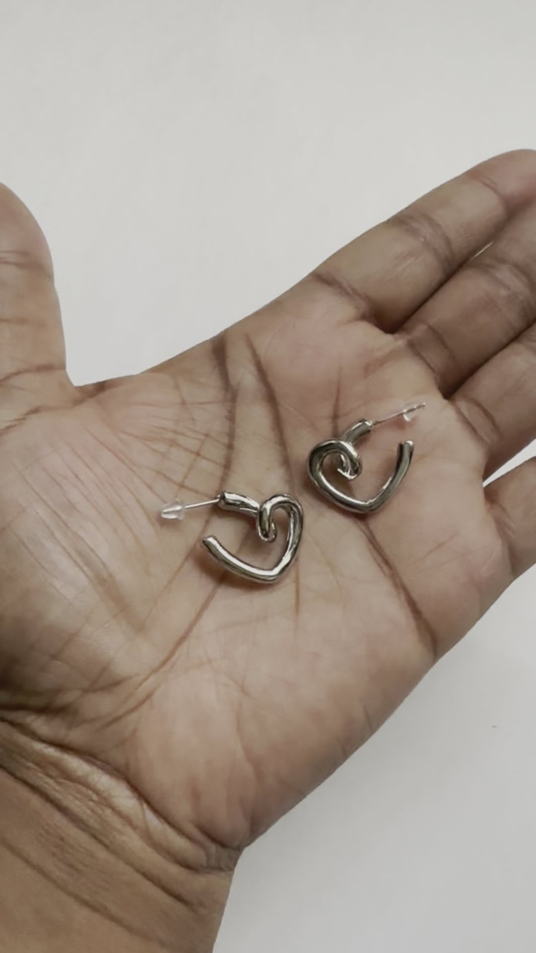 A real-time view of our You Are Love Earrings shown on the palm of model's hand.