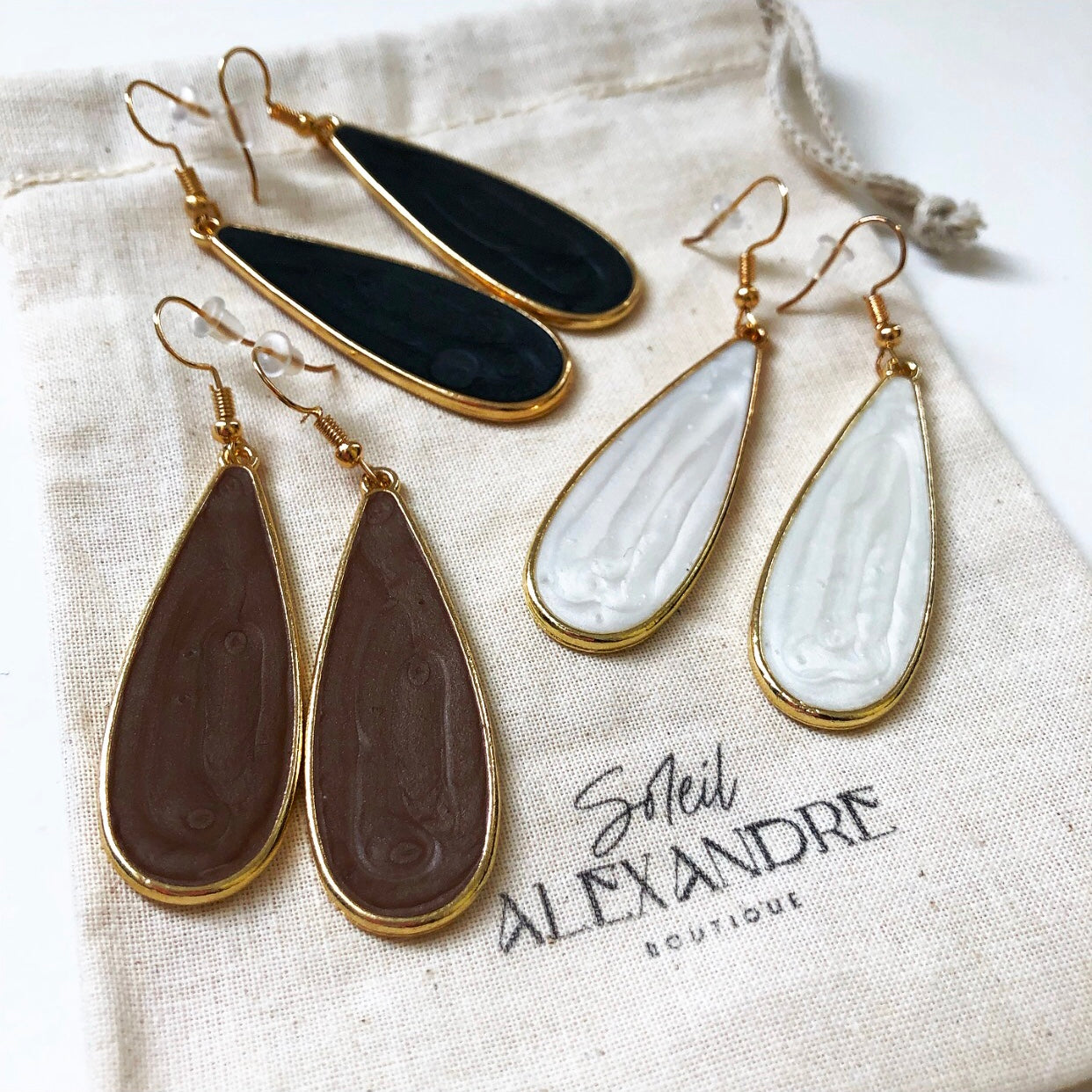 Black, White, and Taupe Candy Rain Drop Earring variations styled on our drawstring jewelry bag.