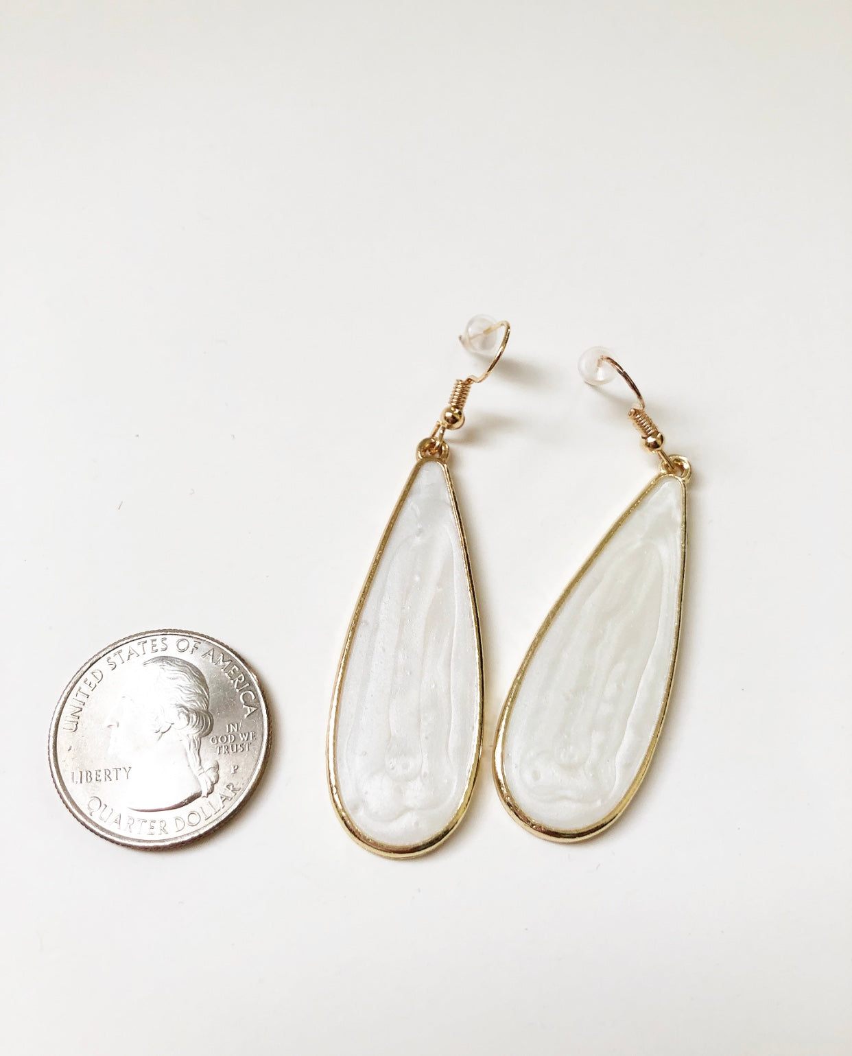 White Candy Rain Drop Earrings next to a quarter for size comparison.