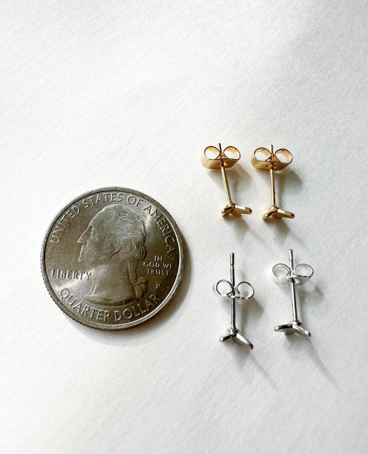 Gold and silver Tiny Flutters Stud Earrings next to a quarter for size comparison.