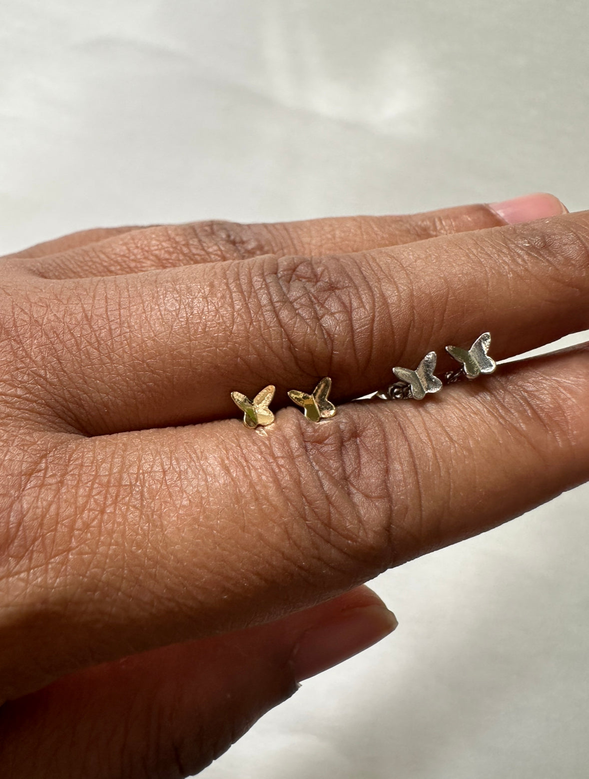 Gold and Silver Tiny Flutters Stud Earrings held by model.