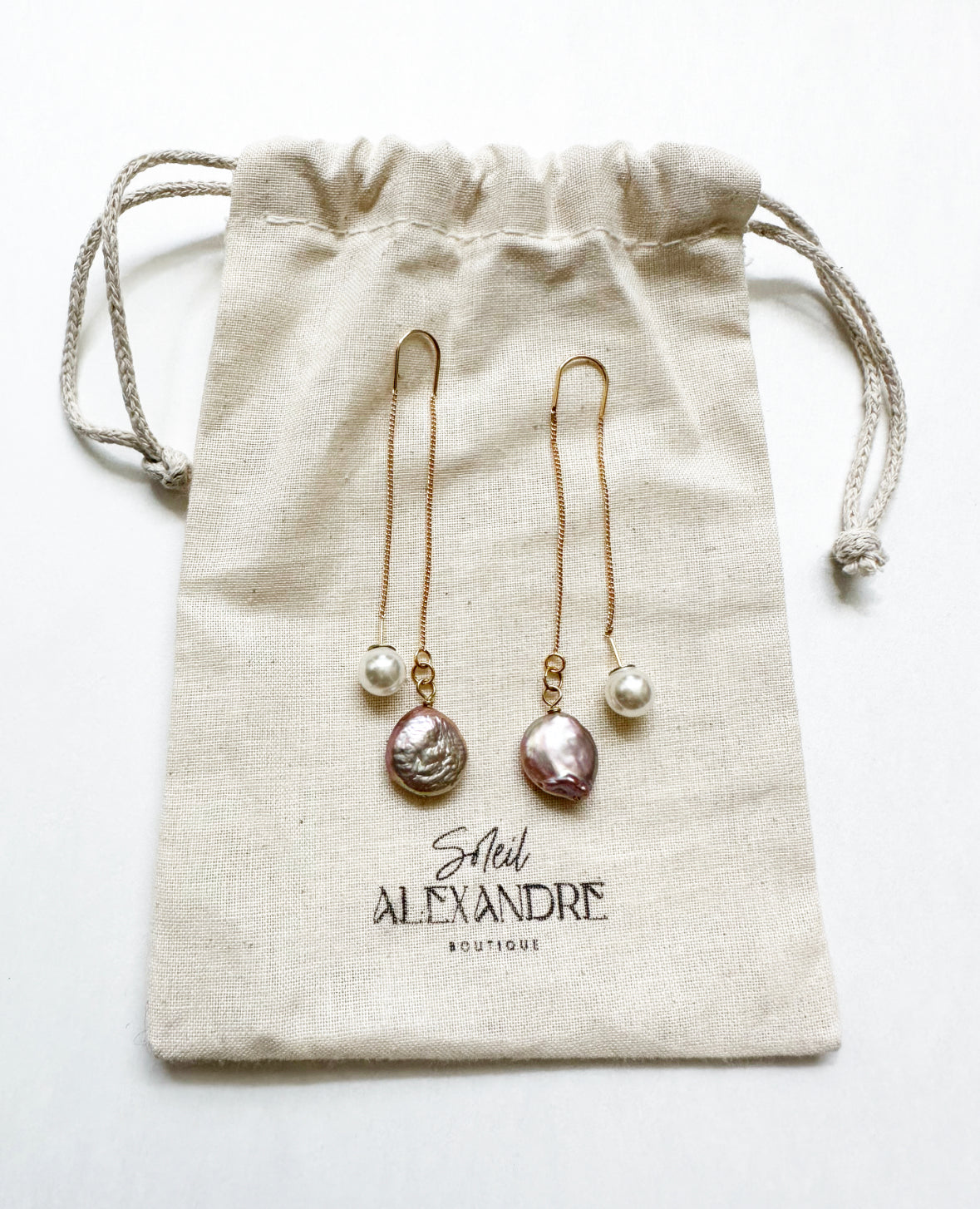 Adorn Earrings shown on our drawstring bag with logo.