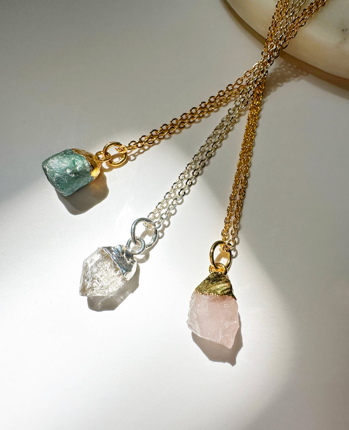 Photo of emerald, Herkimer diamond, and rose quartz necklaces.