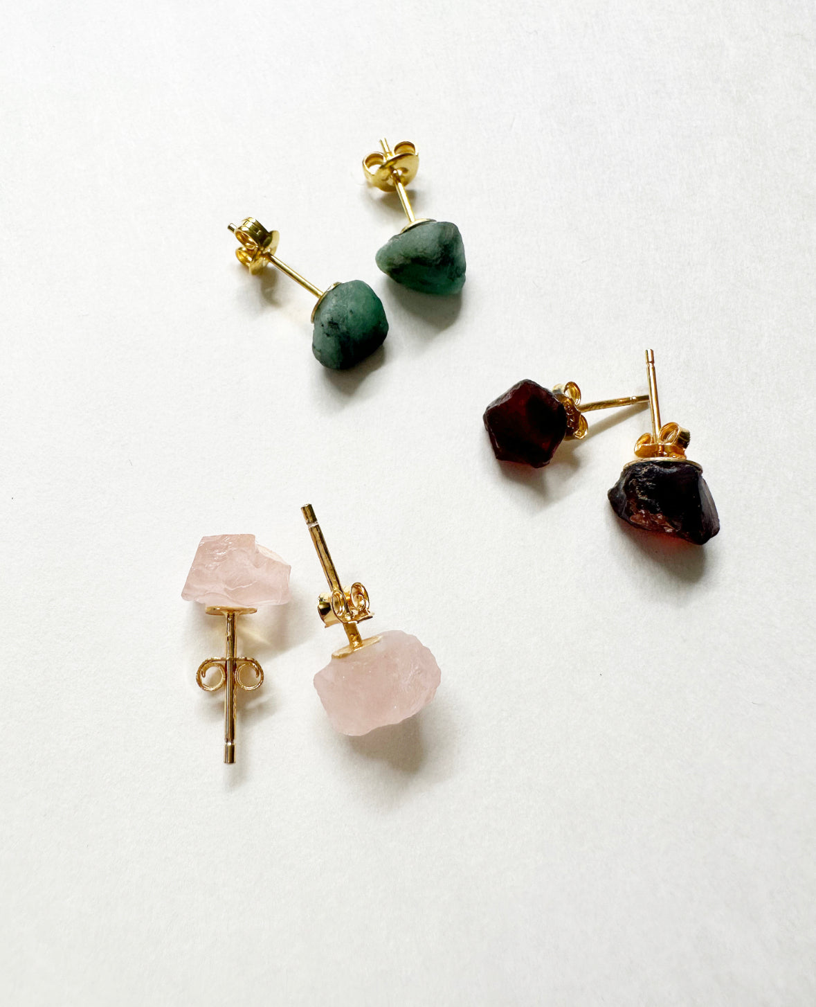 Raw emerald, ruby, and rose quartz stud earrings.