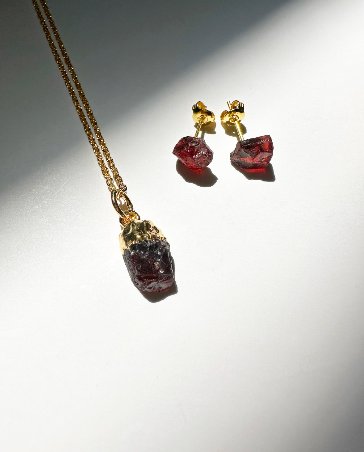 Photo of raw garnet birthstone necklace and matching raw garnet birthstone stud earrings.