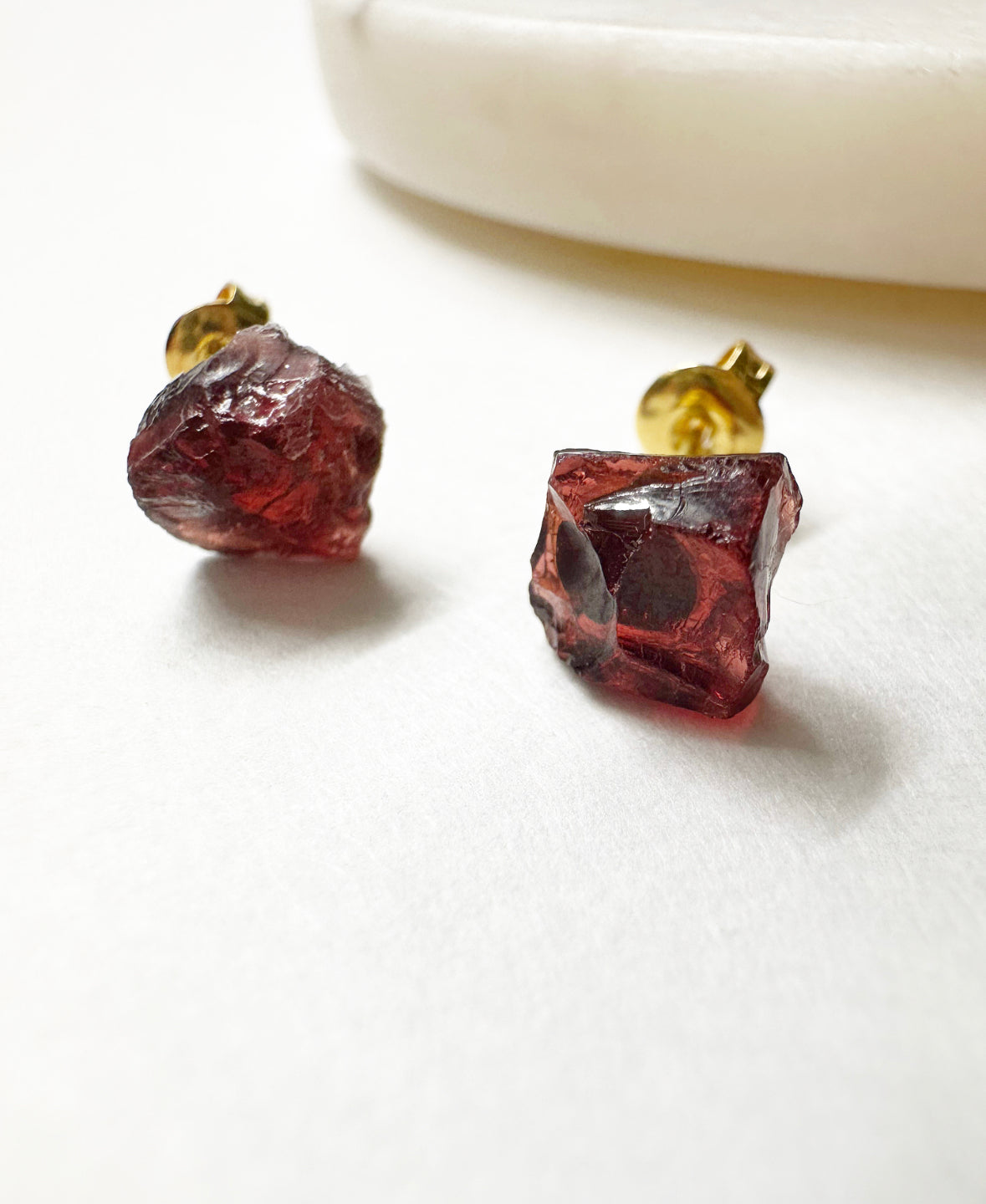 Close-up view of raw garnet stud earrings.