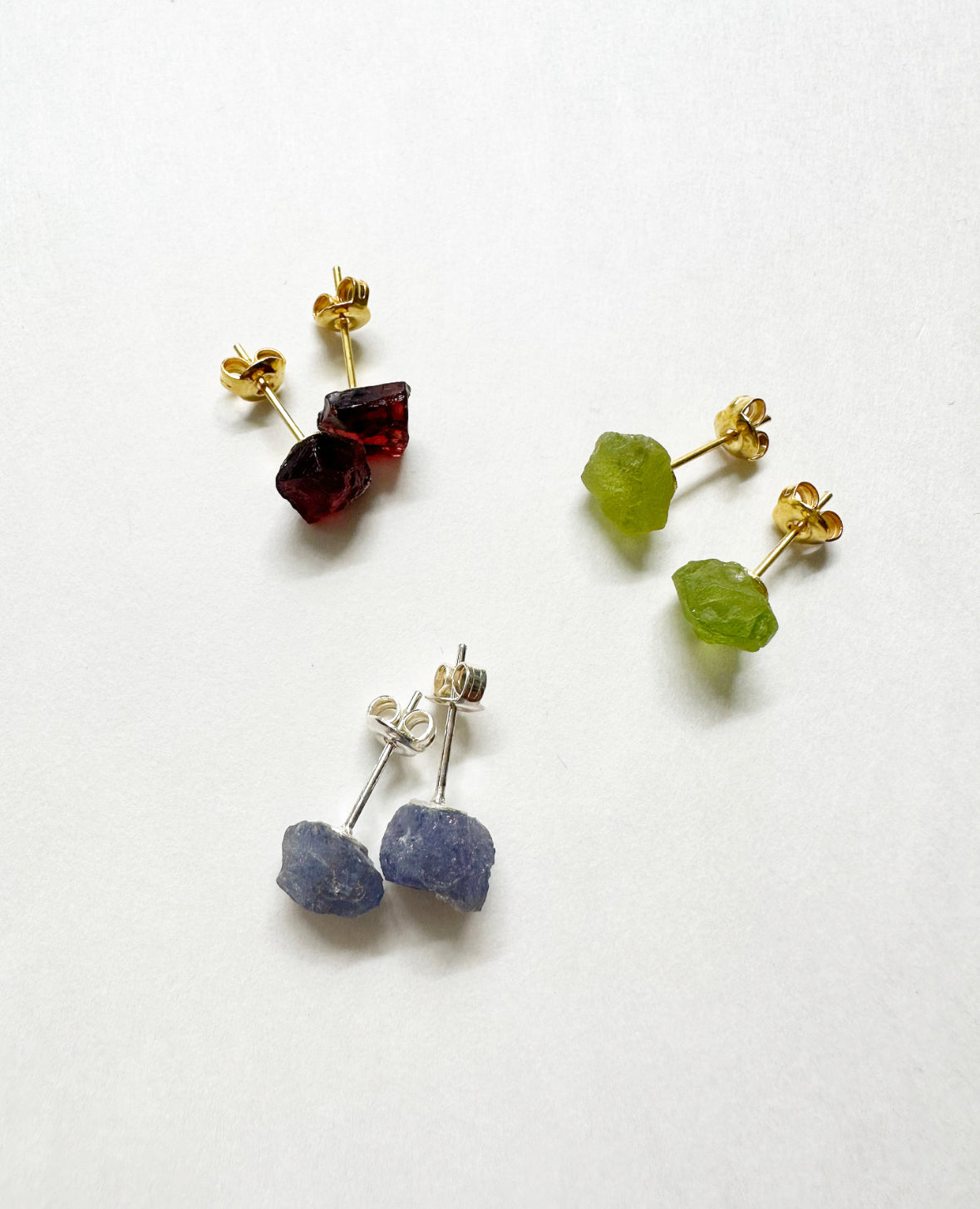 Photo of raw garnet, peridot, and tanzanite stud earrings.