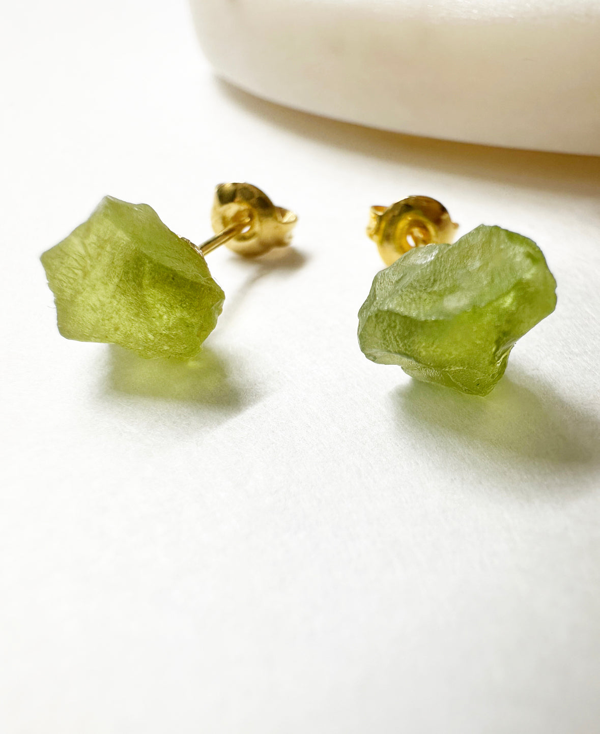 Close-up of raw peridot stud earrings.