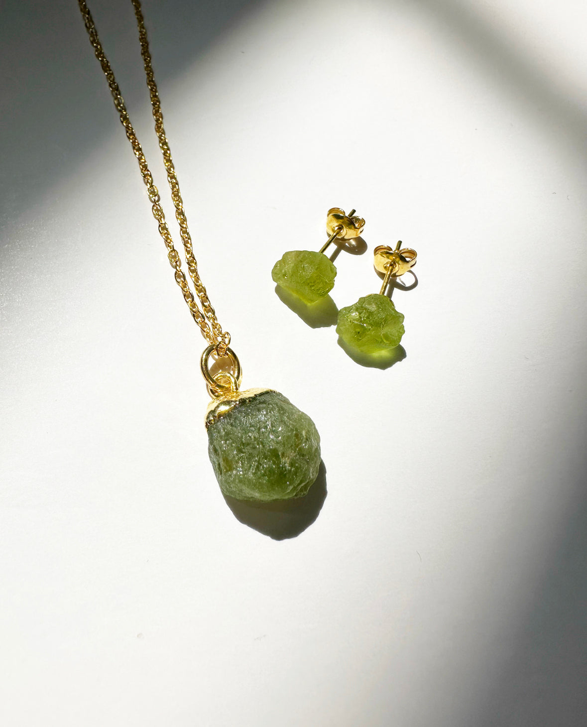 Photo of raw peridot birthstone necklace and matching raw peridot birthstone stud earrings.