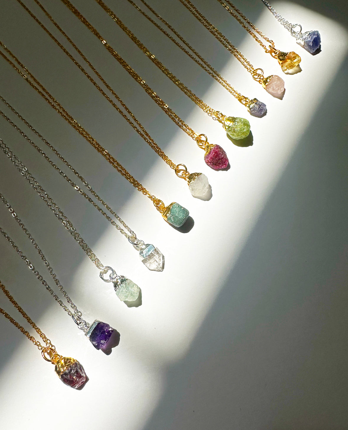 Photo of all twelve raw gemstone birthstone necklaces (January - December).