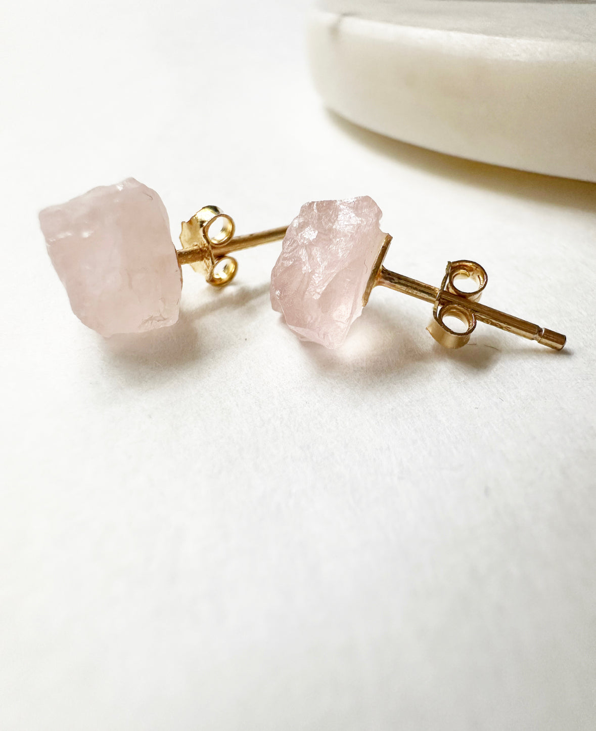 Close-up of raw rose quartz stud earrings.