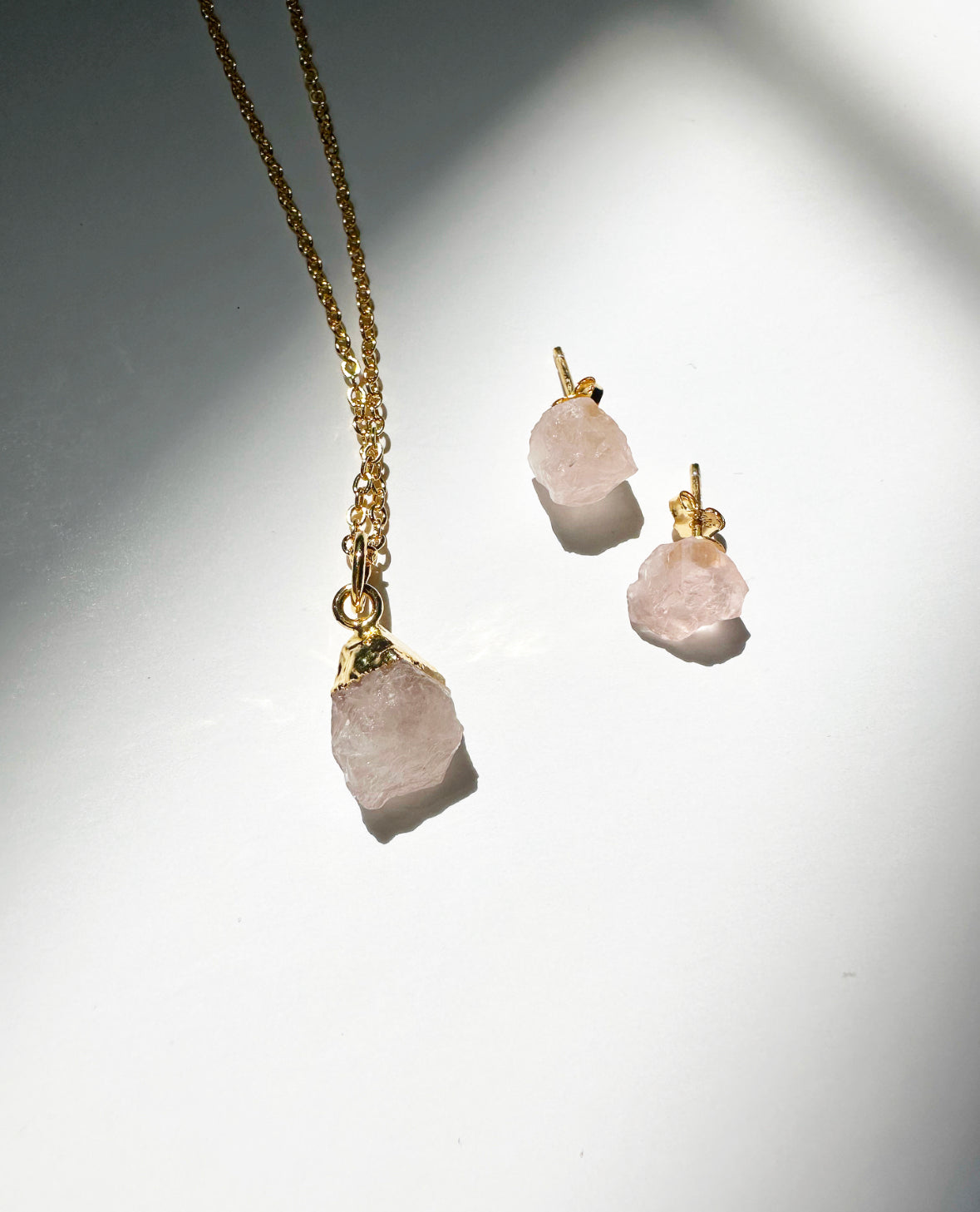 Photo of raw rose quartz birthstone necklace and matching raw rose quartz birthstone stud earrings.