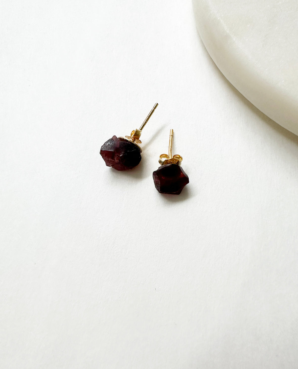 Raw ruby birthstone stud earrings with 14k gold posts.