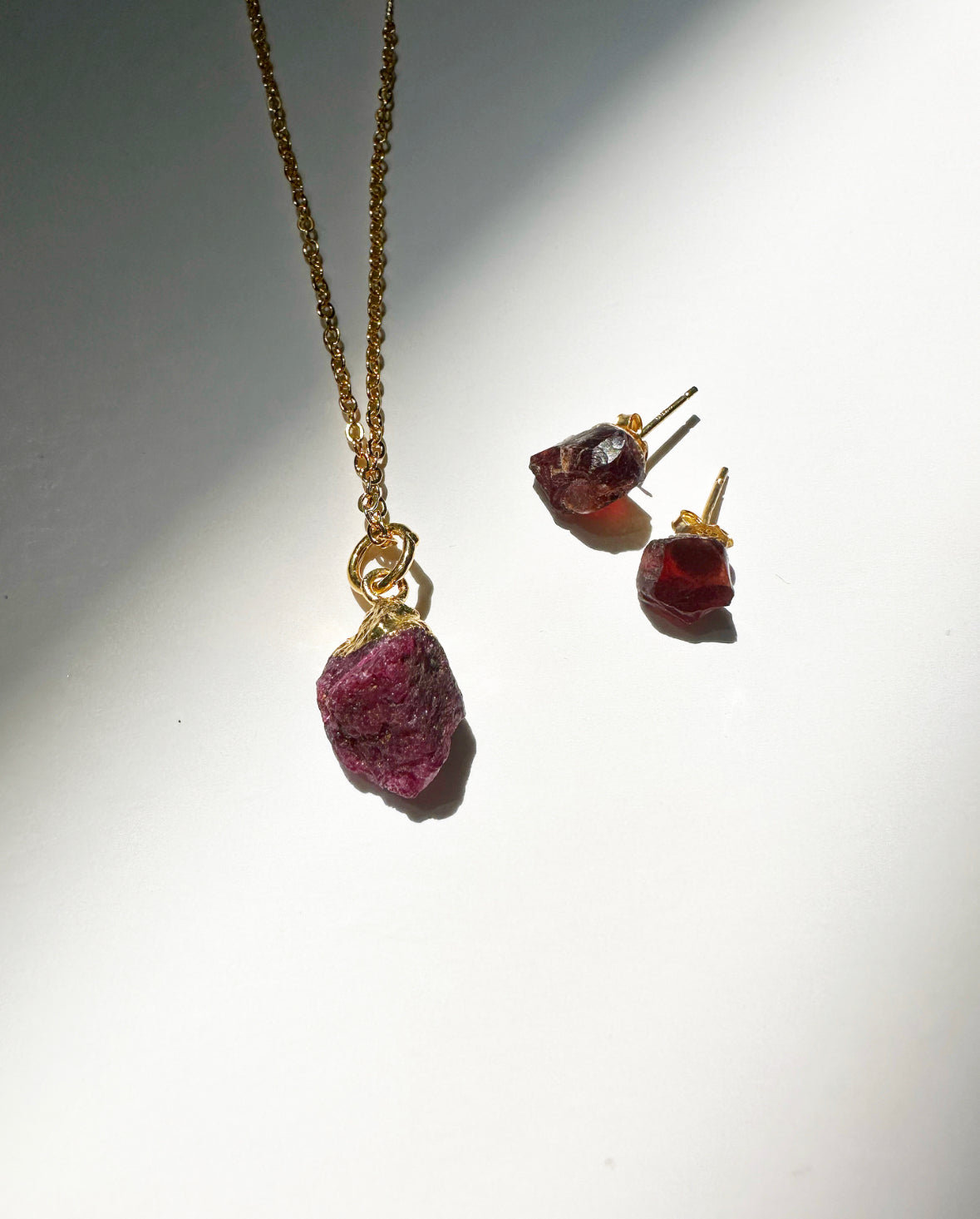 Photo of raw ruby birthstone necklace and matching raw ruby birthstone stud earrings.