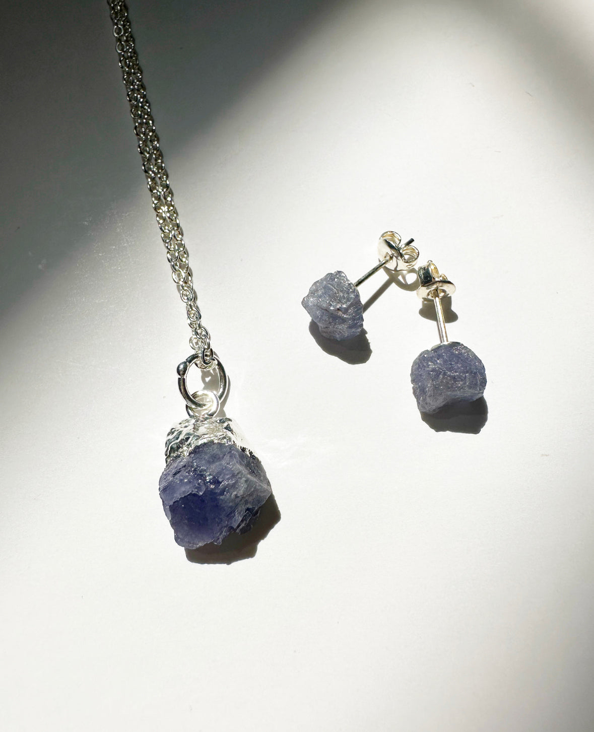 Photo of raw tanzanite birthstone necklace and matching raw tanzanite birthstone stud earrings.