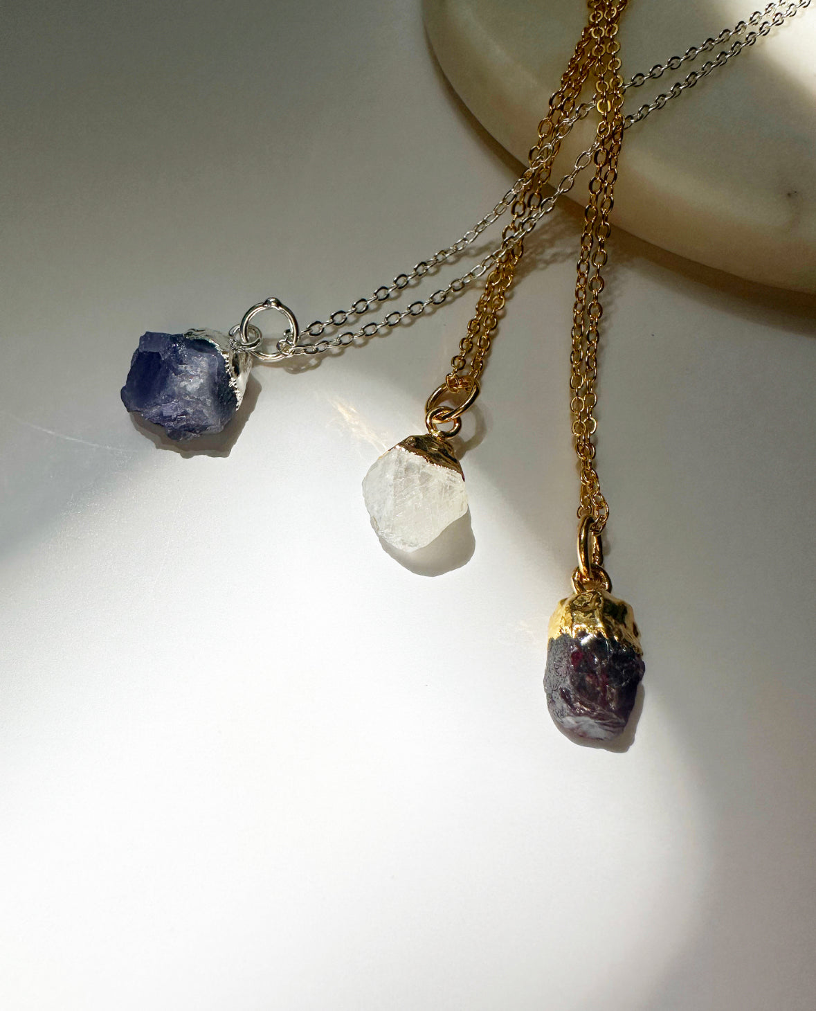 Photo of tanzanite, rainbow moonstone, and garnet necklaces.
