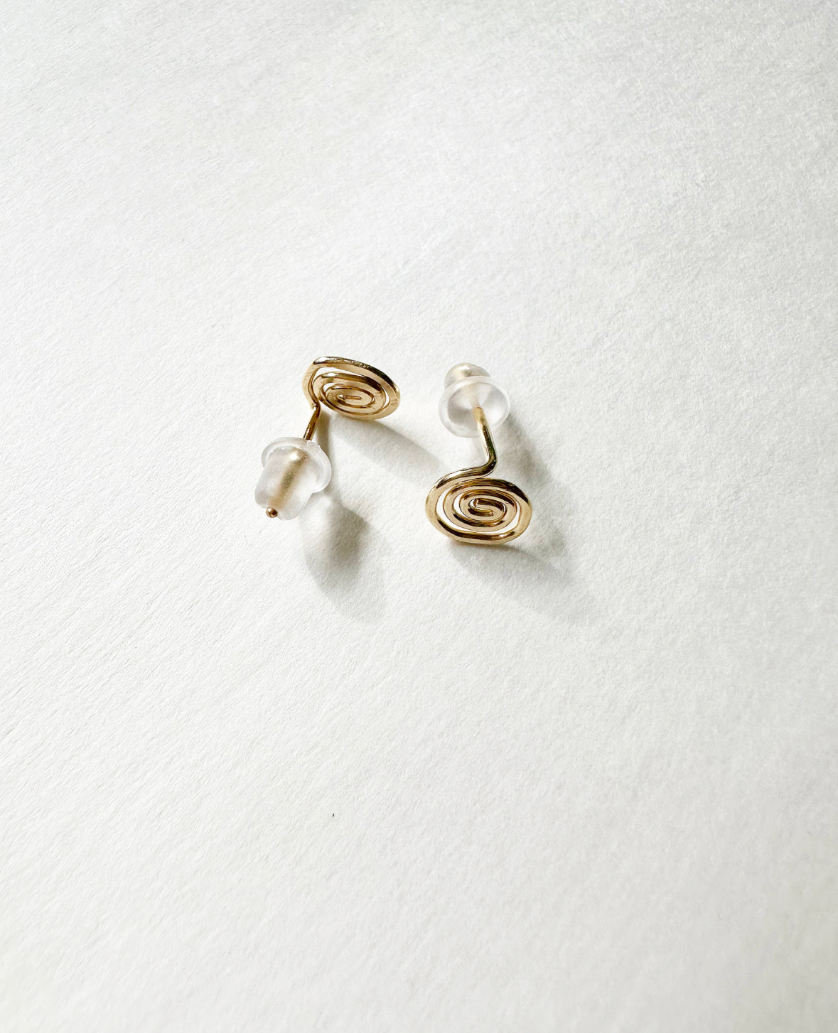 Front and back view of Gold Vortex Studs Earrings with silicone backs.