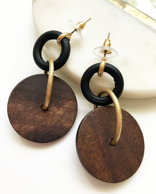 Full view of our Black Coffee Earrings featuring a black wooden hoop and brown textured wooden circle bead connected with matte gold finishings.