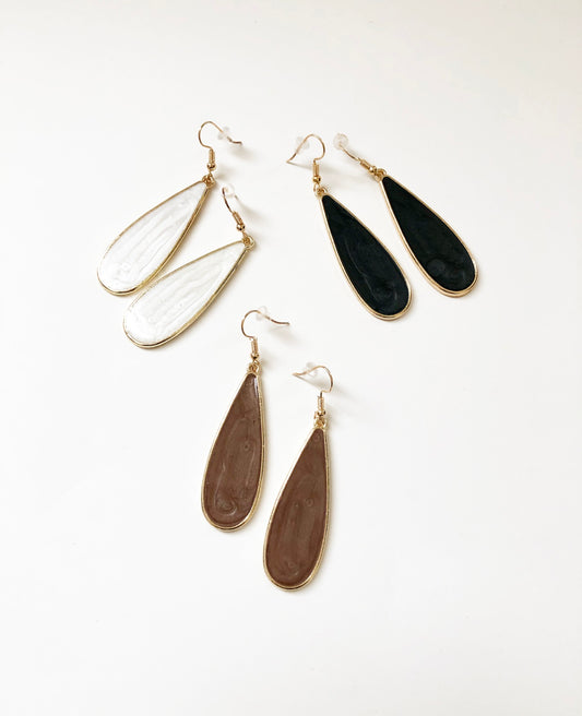 Candy Rain Drop Earrings featuring raindrop-shaped pendants with white, black, or taupe opaque pearlized acrylic filled centers. One pair of each color is shown.