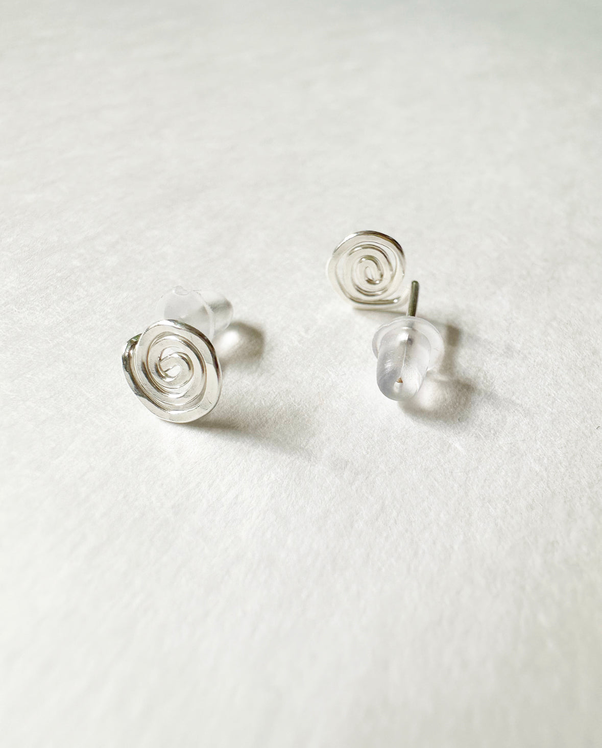 Front and back view of Silver Vortex Stud Earrings with silicone backs.