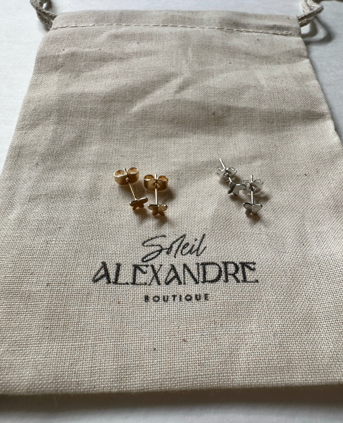 Gold and Silver Tiny Flutters Stud Earrings styled on our drawstring jewelry bag.