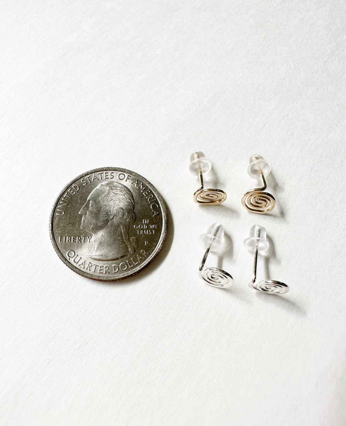 Gold and Silver Vortex Stud Earrings compared to a quarter for size comparison.