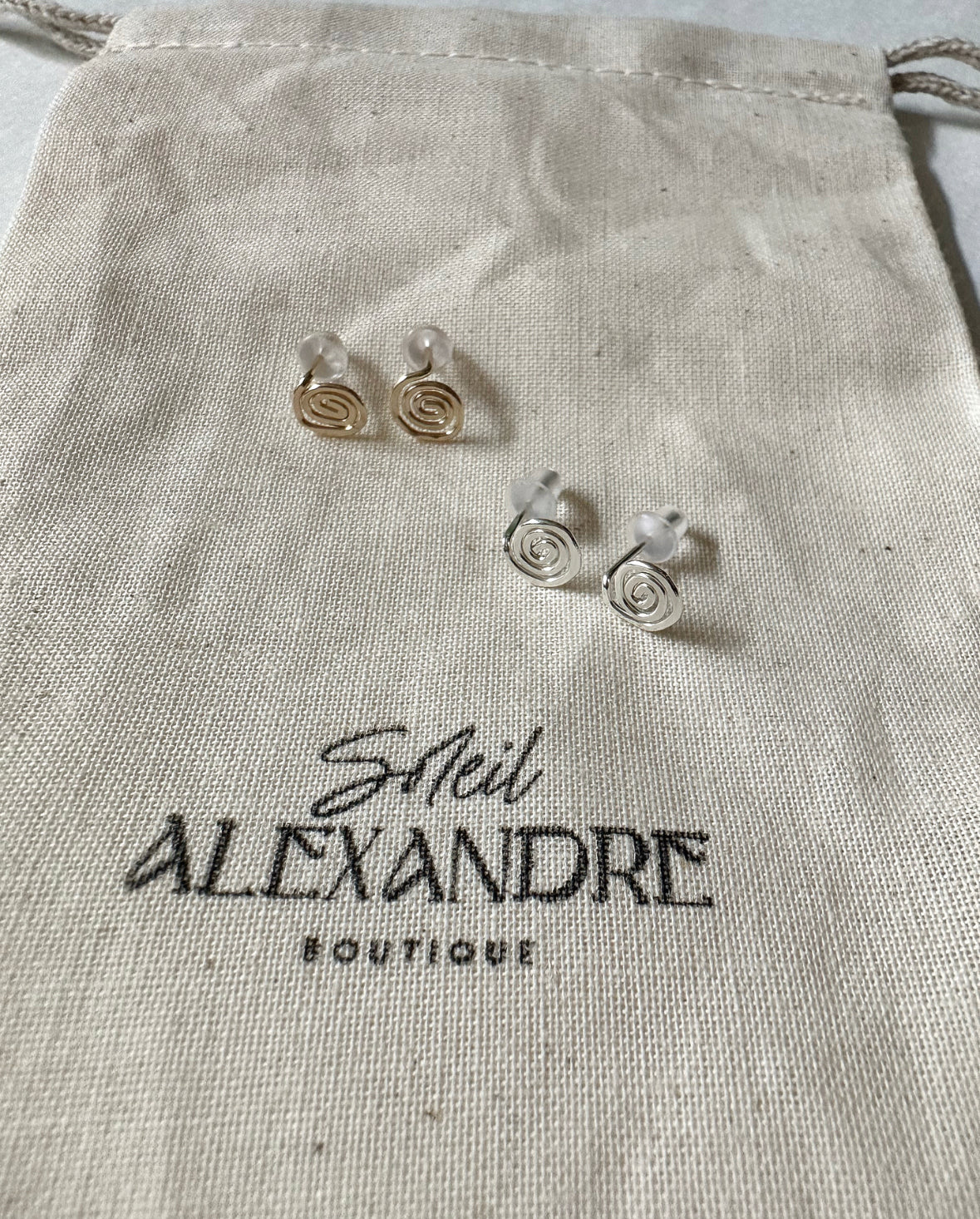 Gold and Silver Vortex Stud Earrings styled on top of our drawstring jewelry bag.